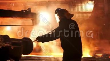 炼钢工人从冶金厂的感应坩埚熔炼炉中除渣，工作辛苦